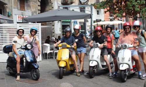 A group of tourists riding a vespa, on a vespa tour in Naples, Italy.