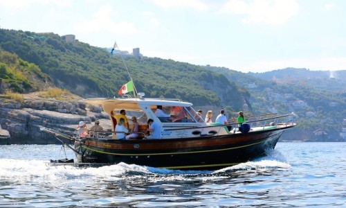 Boat cruising with tourists on a sunny day. Naples Italy coastline.